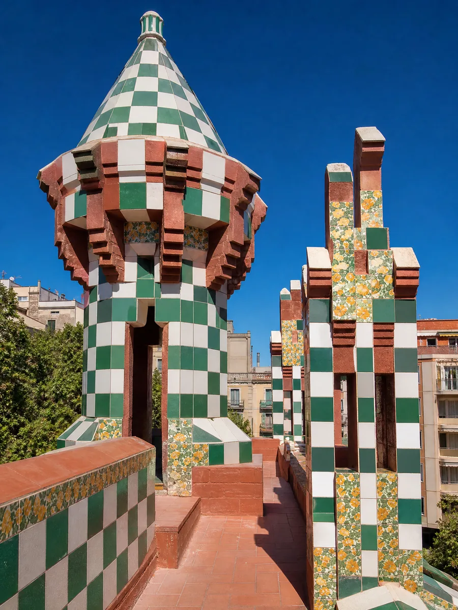 A small tiled turret and chimneys in green and white on a rooftop against a blue sky